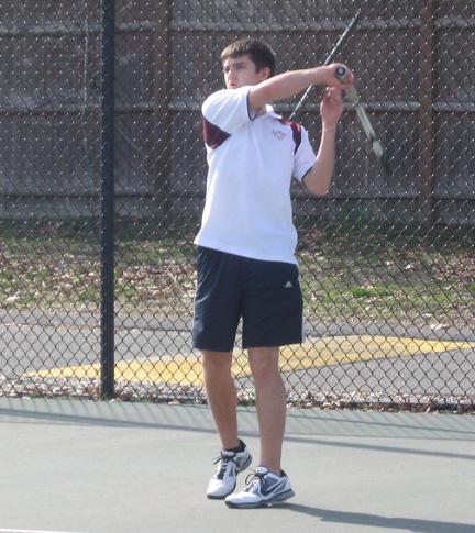 Sophomore Ian Dansereau returns a serve on the second singles court.