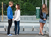 Teenage girl looking jealously at happy teenage couple waiting at bus stop