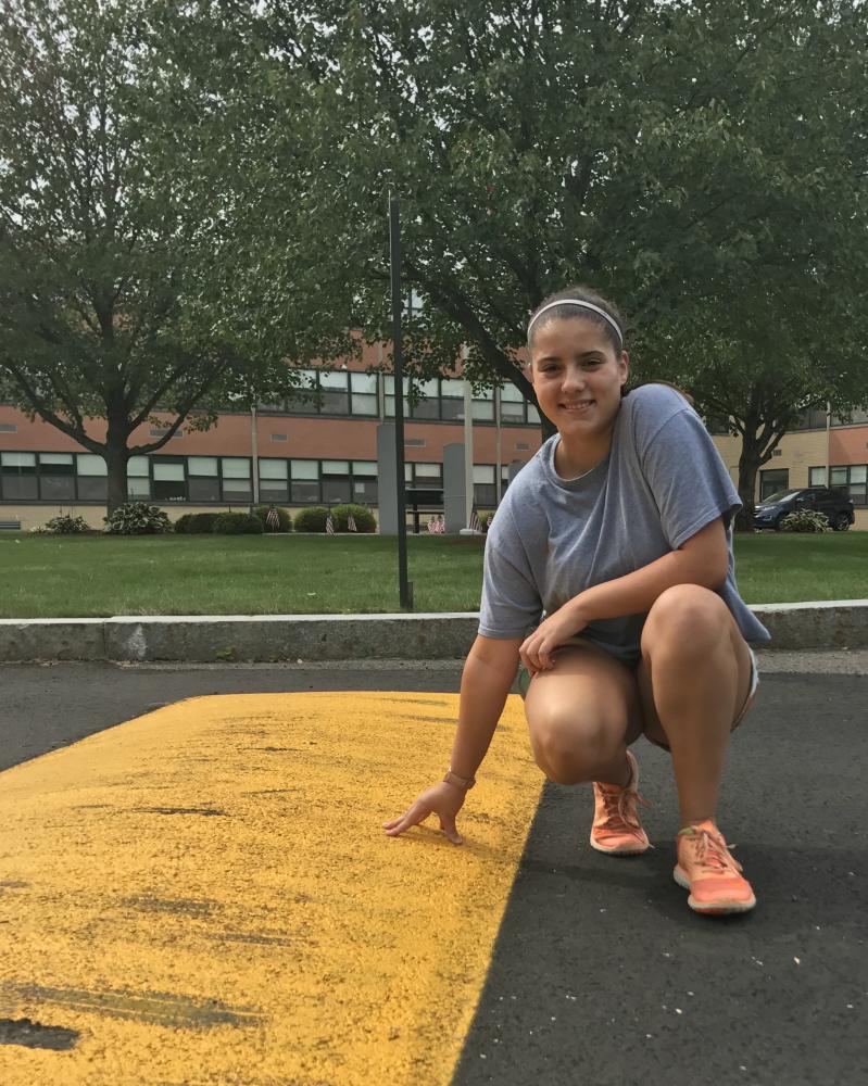 Senior Destiny Lavertue poses next to one of the speed bumps along the back road to the LHS student parking lot.