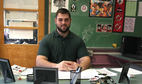 LHS 2013 graduate Ernad Minic sits behind his teachers desk as a long term English substitute.