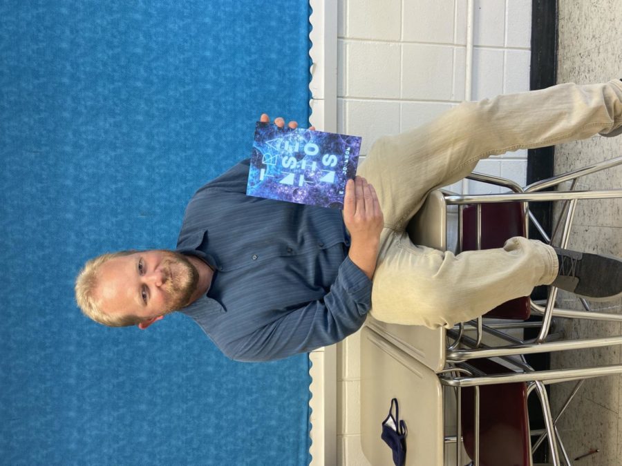 Dr, Johnson, English teacher, poses with his new book of poetry.